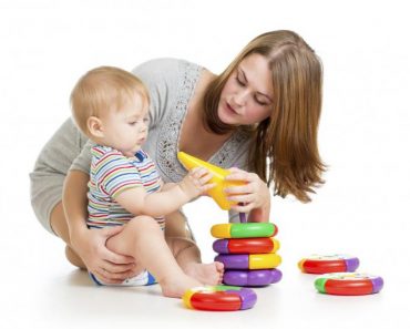 baby boy and mother playing together with construction set toy handing toy to mother 370x297 1