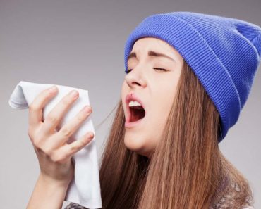 Sick young woman with a flu sneezing closeup over grey Siberia Video and Photos.jpg 370x297 1